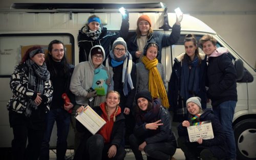 The cast and crew of IRIS, standing in front of a parked van